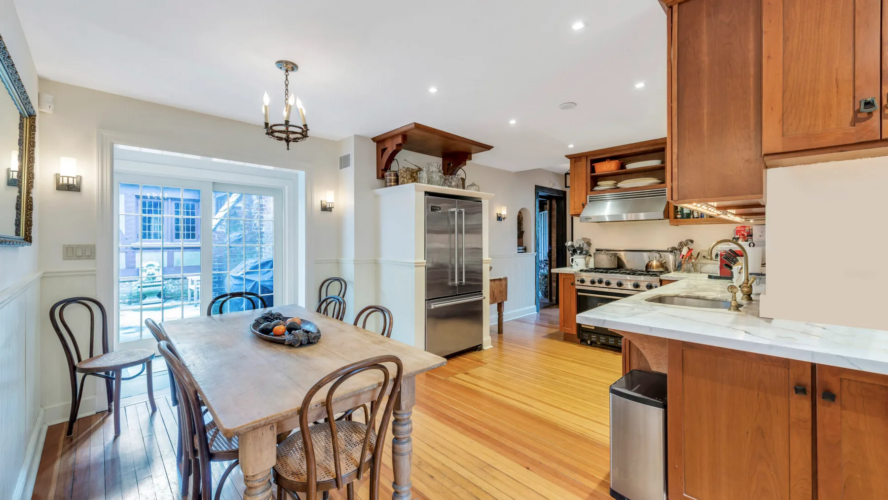 Una cocina luminosa con comedor y una mesa de madera junto a grandes ventanas.