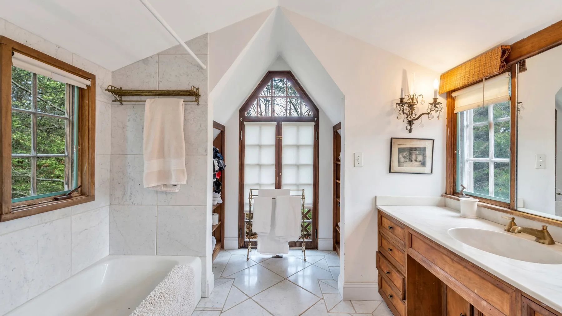 Un baño luminoso tiene una bañera, un tocador y una ventana alta.