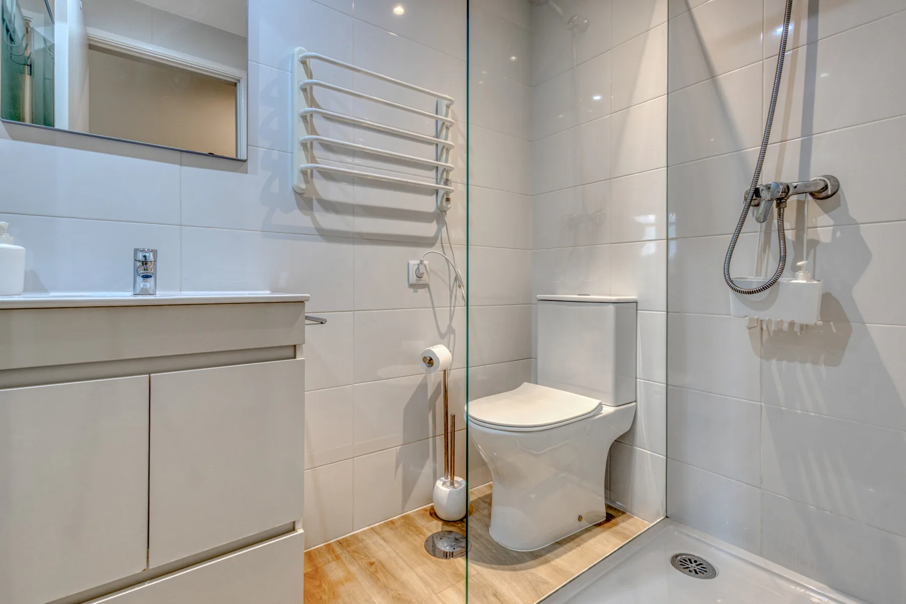 A tiled bathroom with a vanity, toilet, and shower.