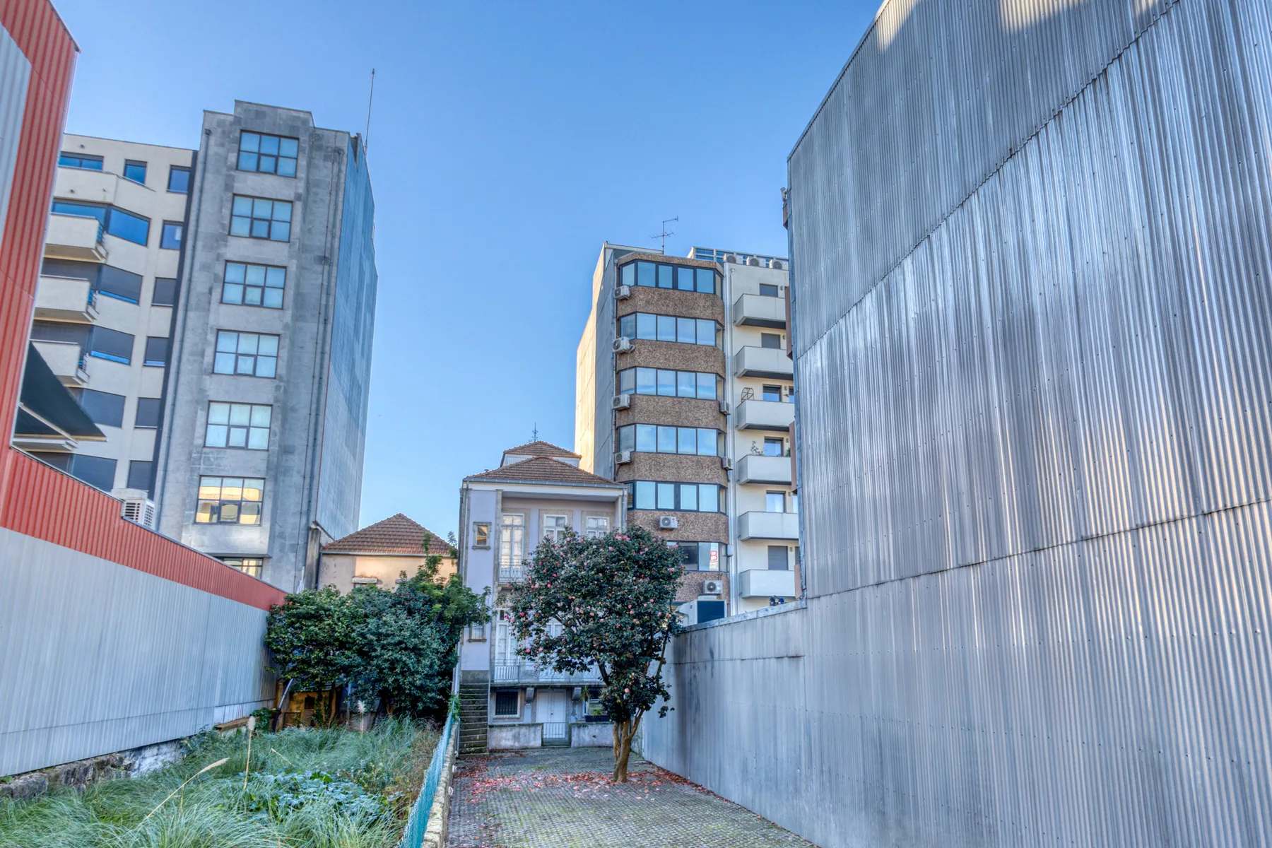 Urban courtyard framed by tall buildings under a clear blue sky.