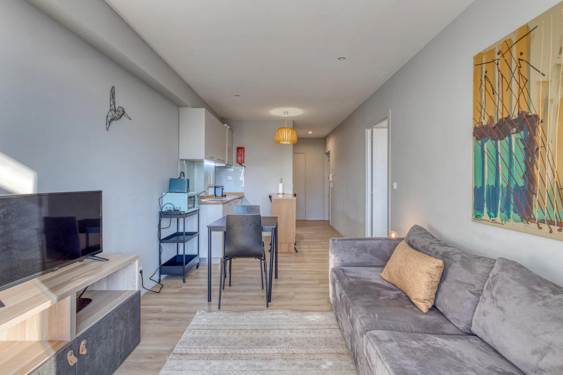 A living room with a television, dining table, and gray seating.