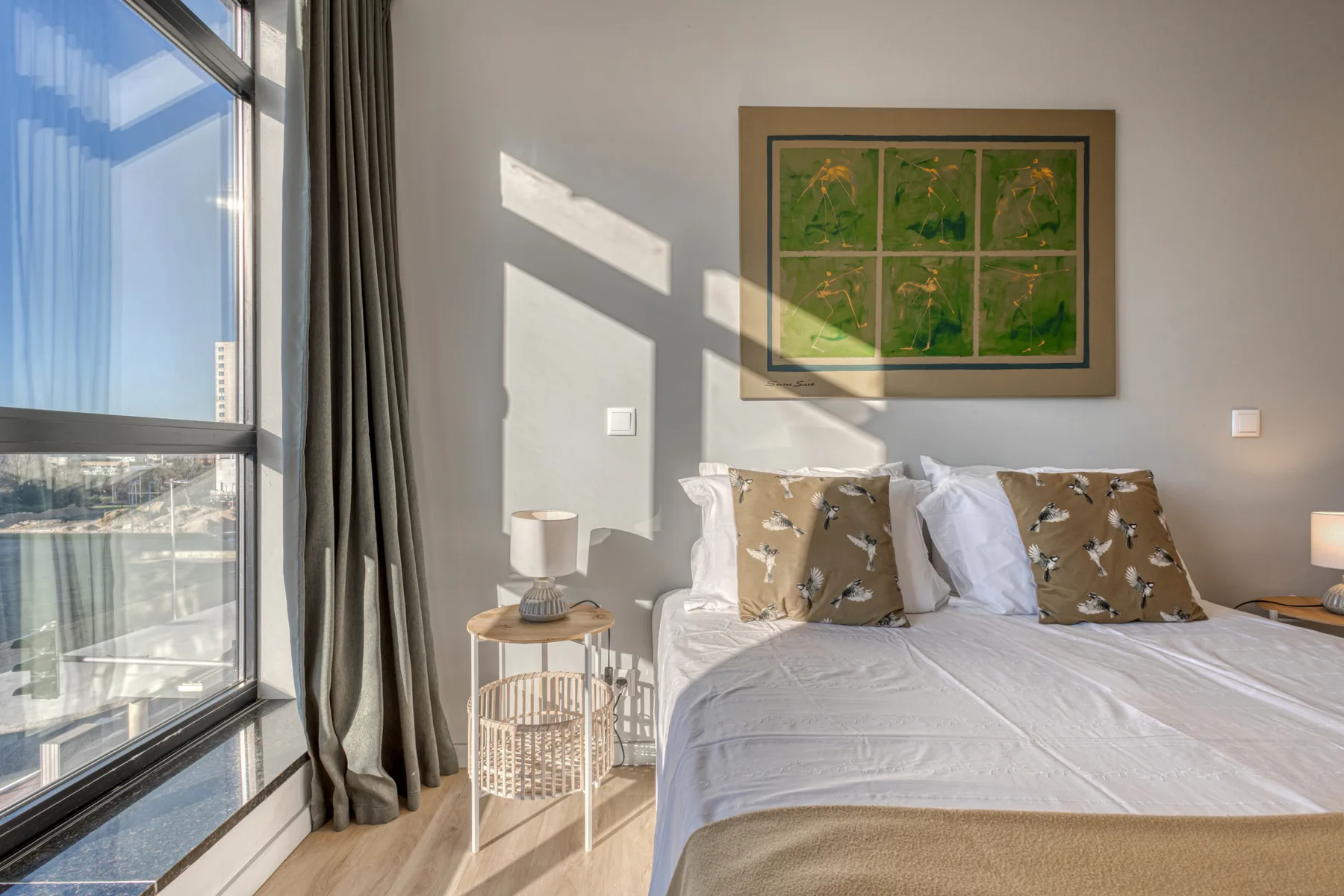 A bedroom with a neatly made bed beside a large window.