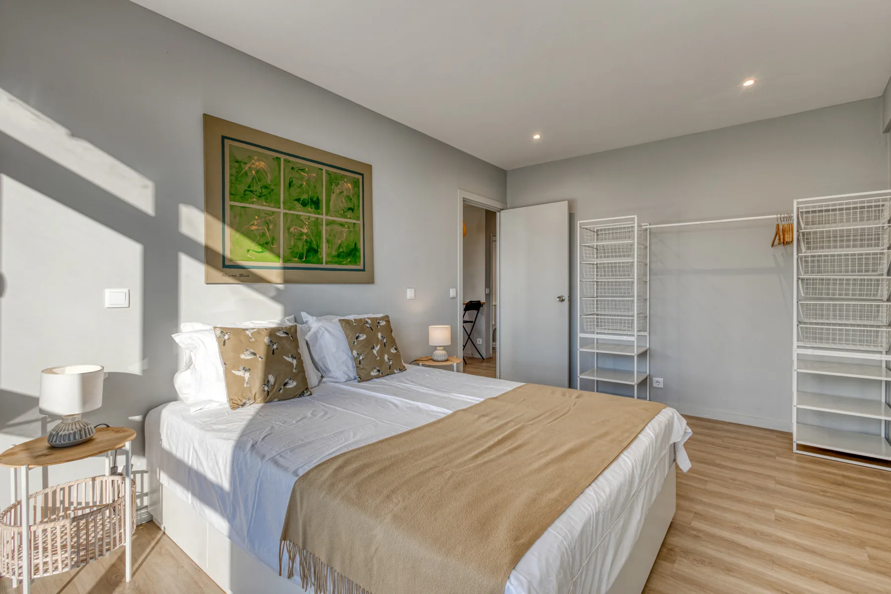 A bedroom with a neatly made bed and open clothing racks.
