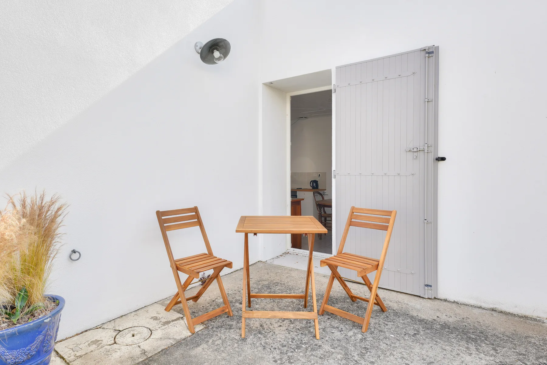 A small outdoor seating area with a wooden table and two folding chairs.