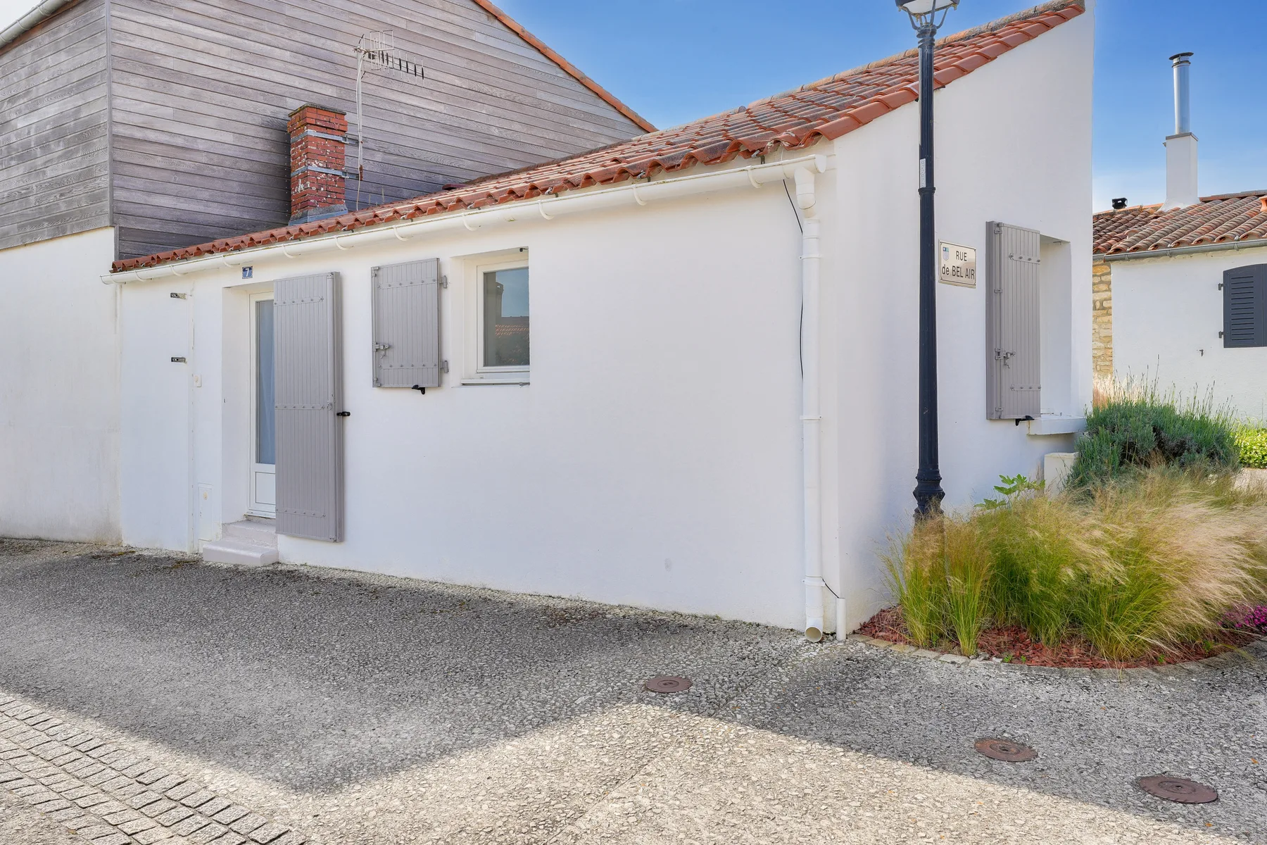 A white cottage exterior with gray shutters and a paved path.