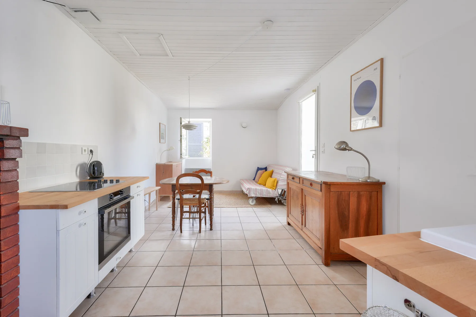 A bright open-plan kitchen and dining area with a table and seating.