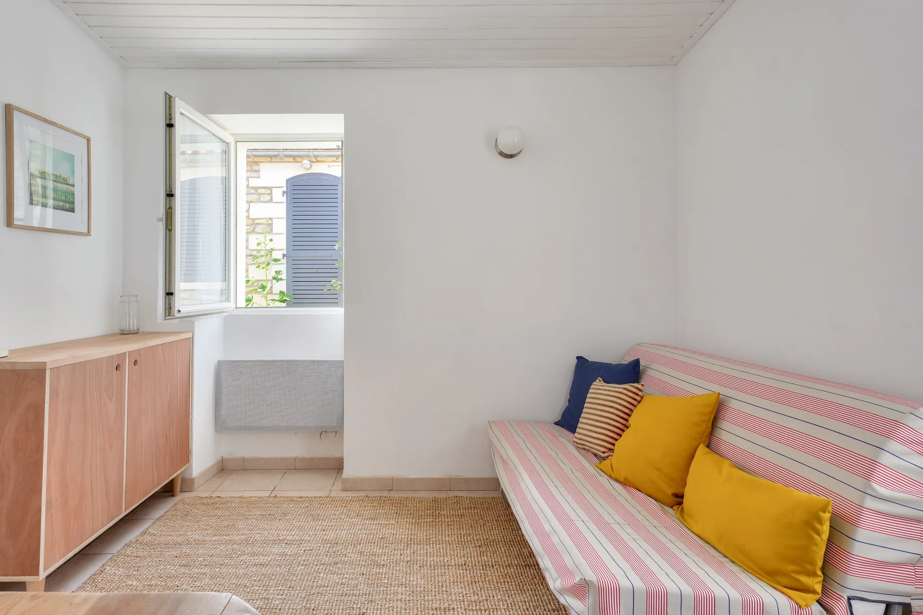 A bright sitting room with striped seating and an open window.