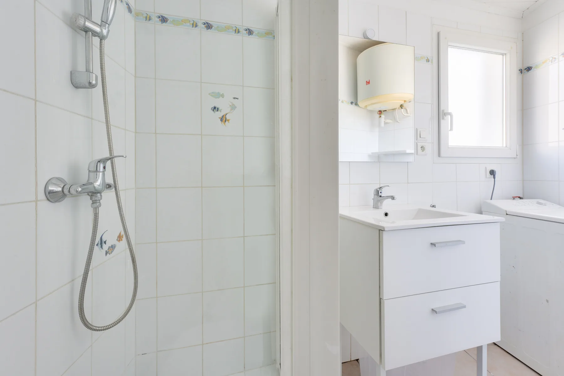 A bright bathroom with a shower, sink, and window.
