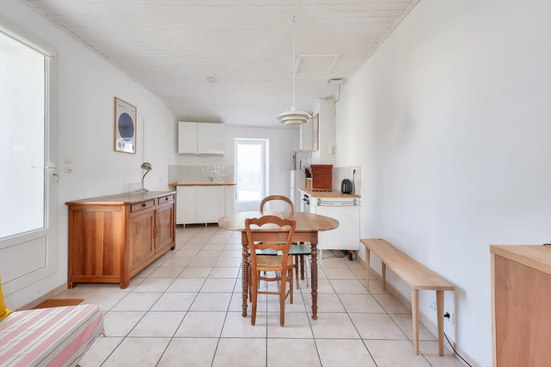 A bright kitchen and dining area with a wooden table and bench.