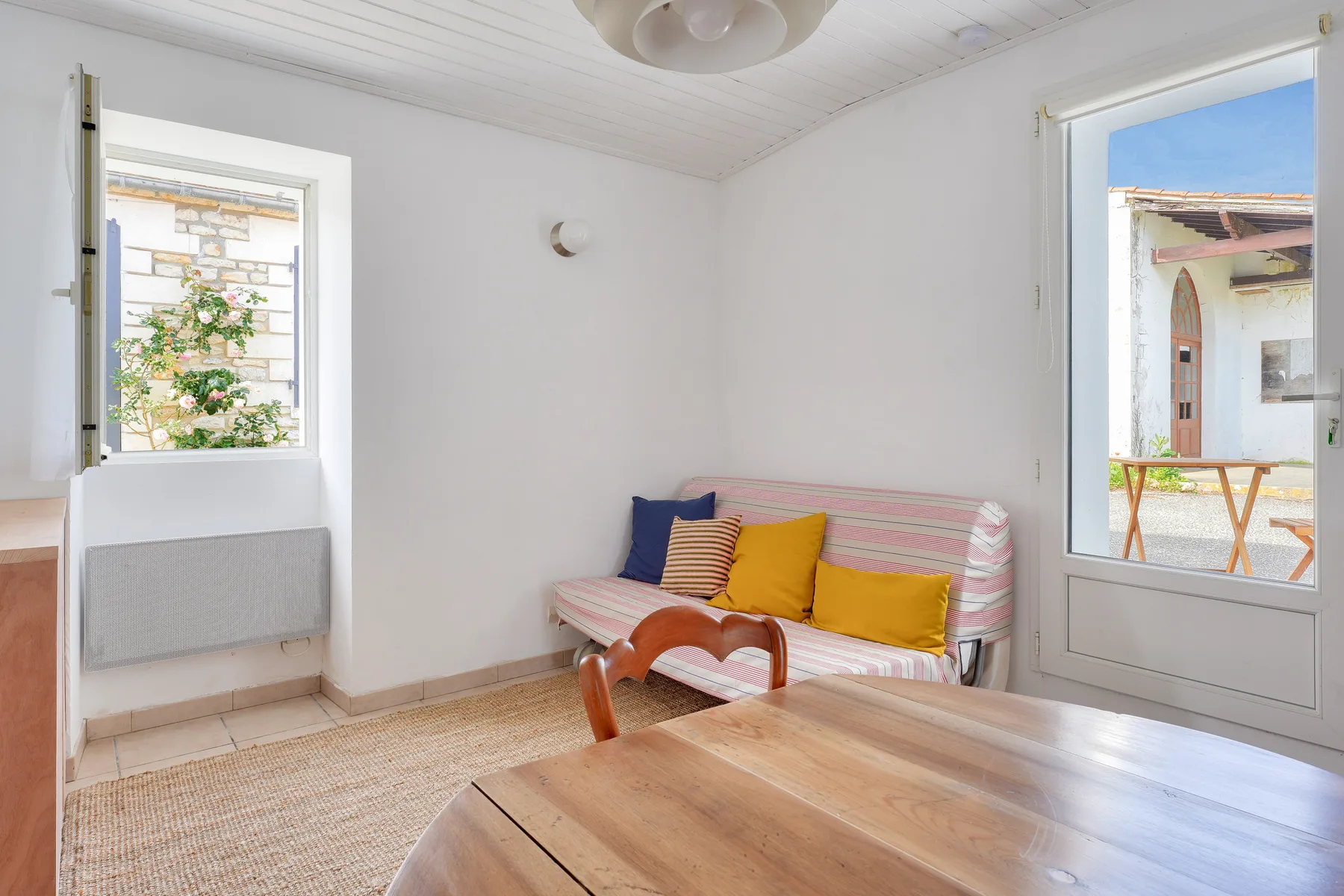 A bright sitting room with a striped settee and wooden table.