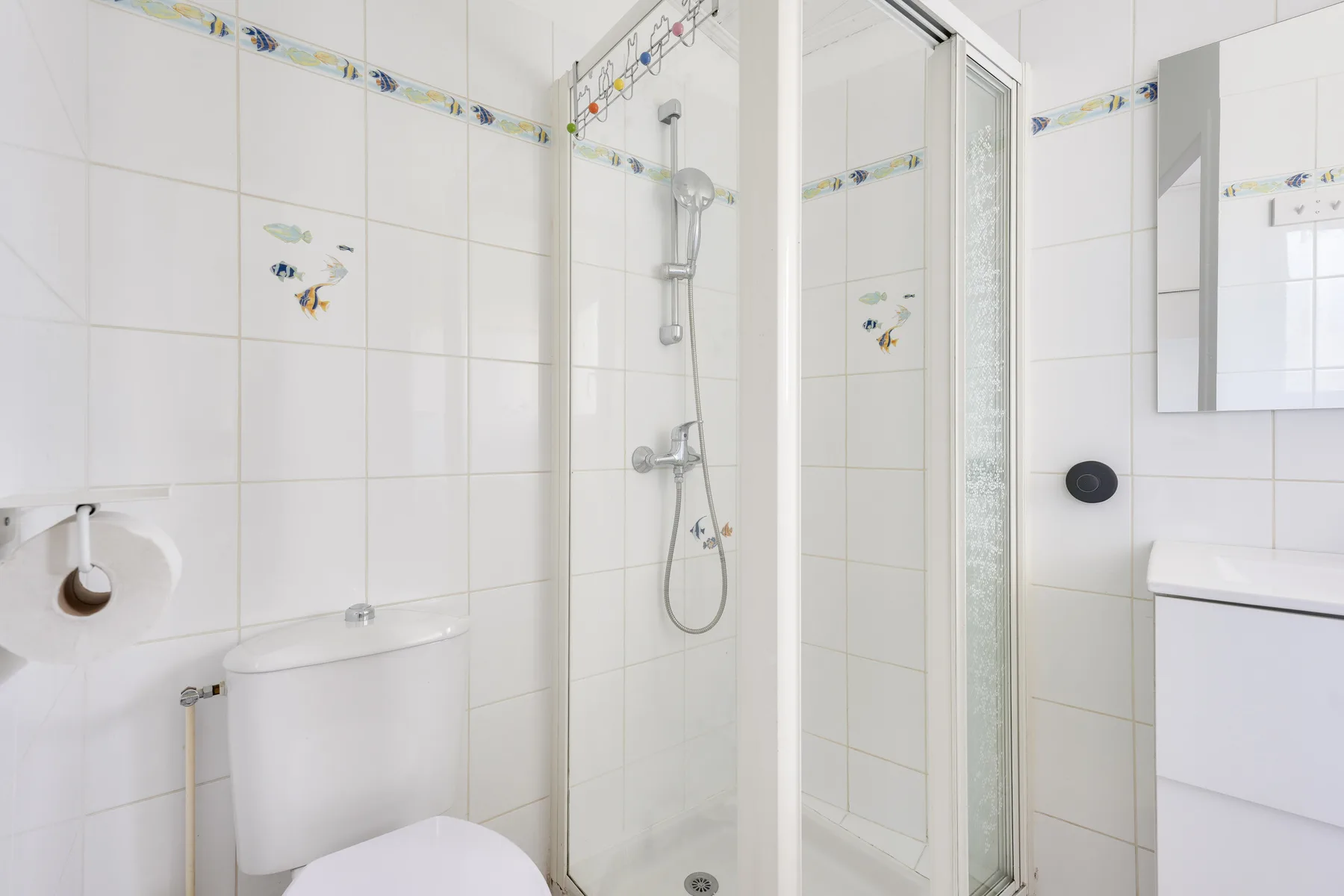 A tiled bathroom with a shower, toilet, and sink.