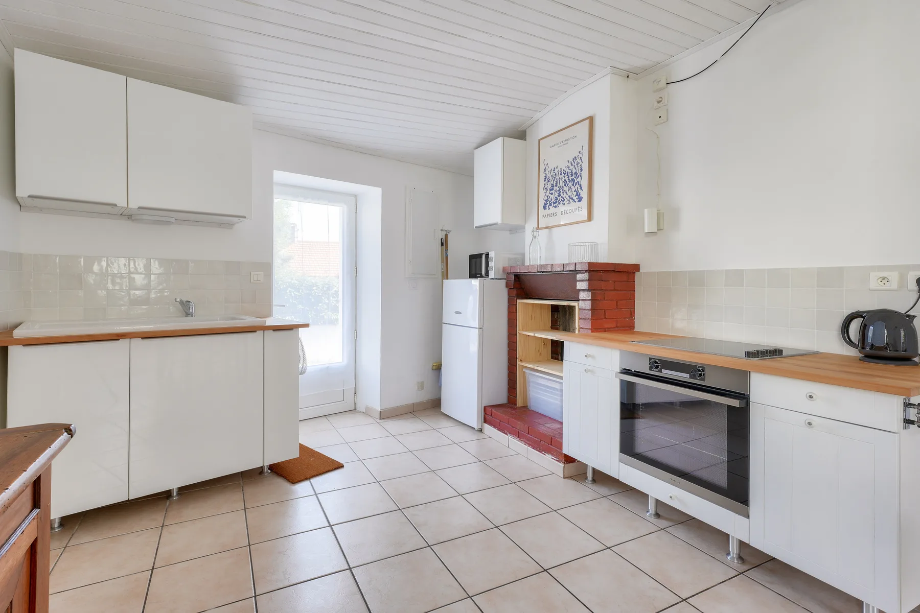 A bright kitchen with white cabinetry, tiled floors, and a built-in oven.