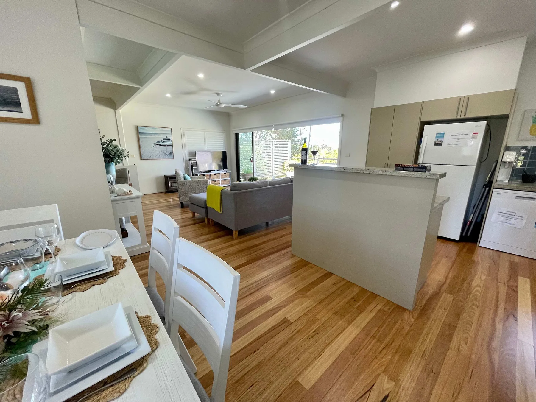 An open-plan living and dining room with a kitchen and large windows.