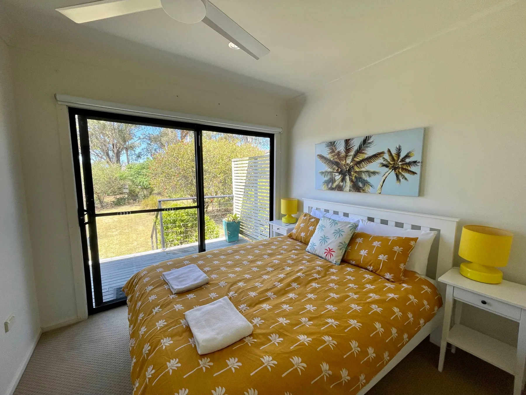 A bedroom with a bed beside large sliding glass doors overlooking greenery.