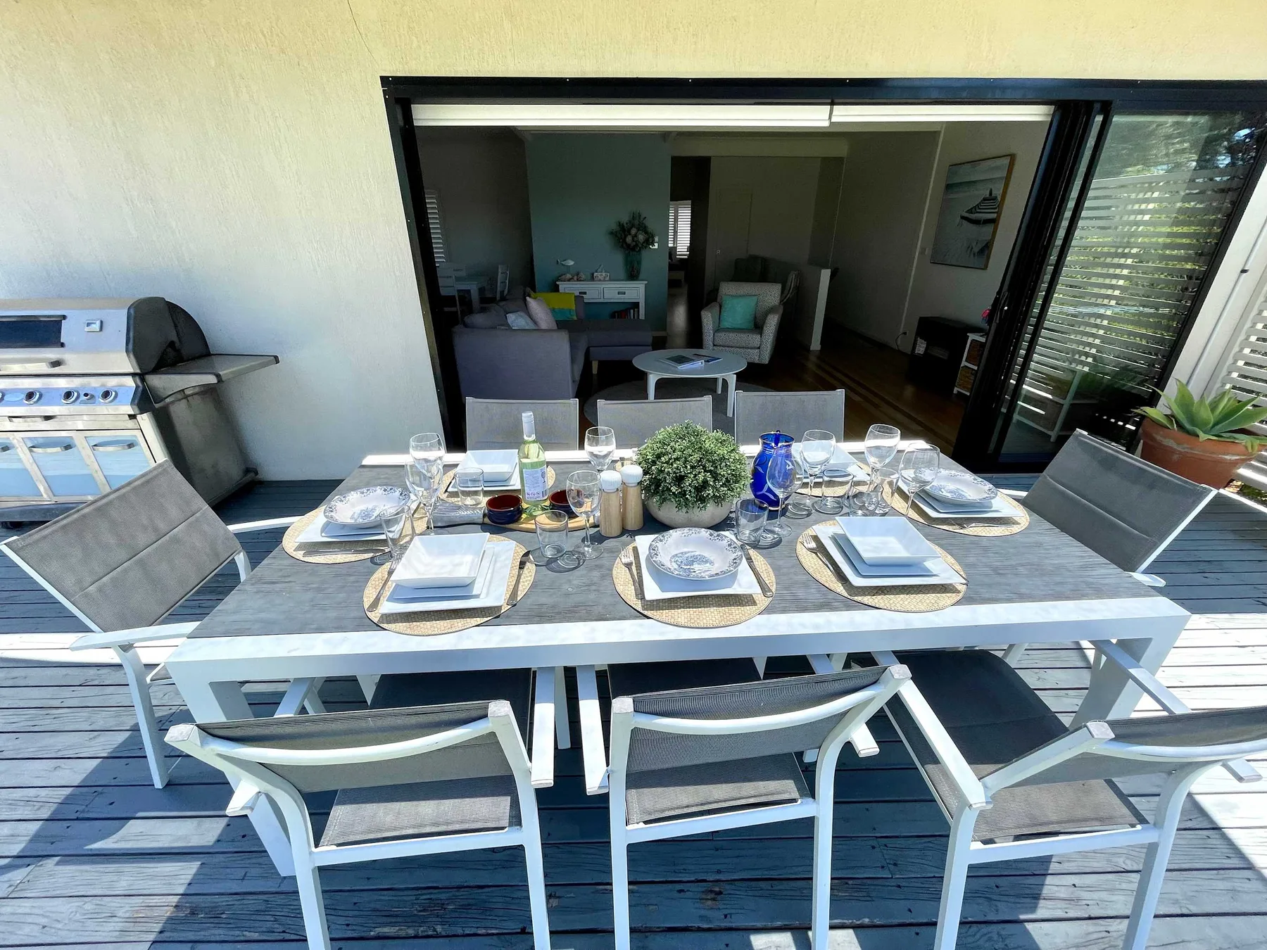 An outdoor dining area has a set table beside an open patio doorway.