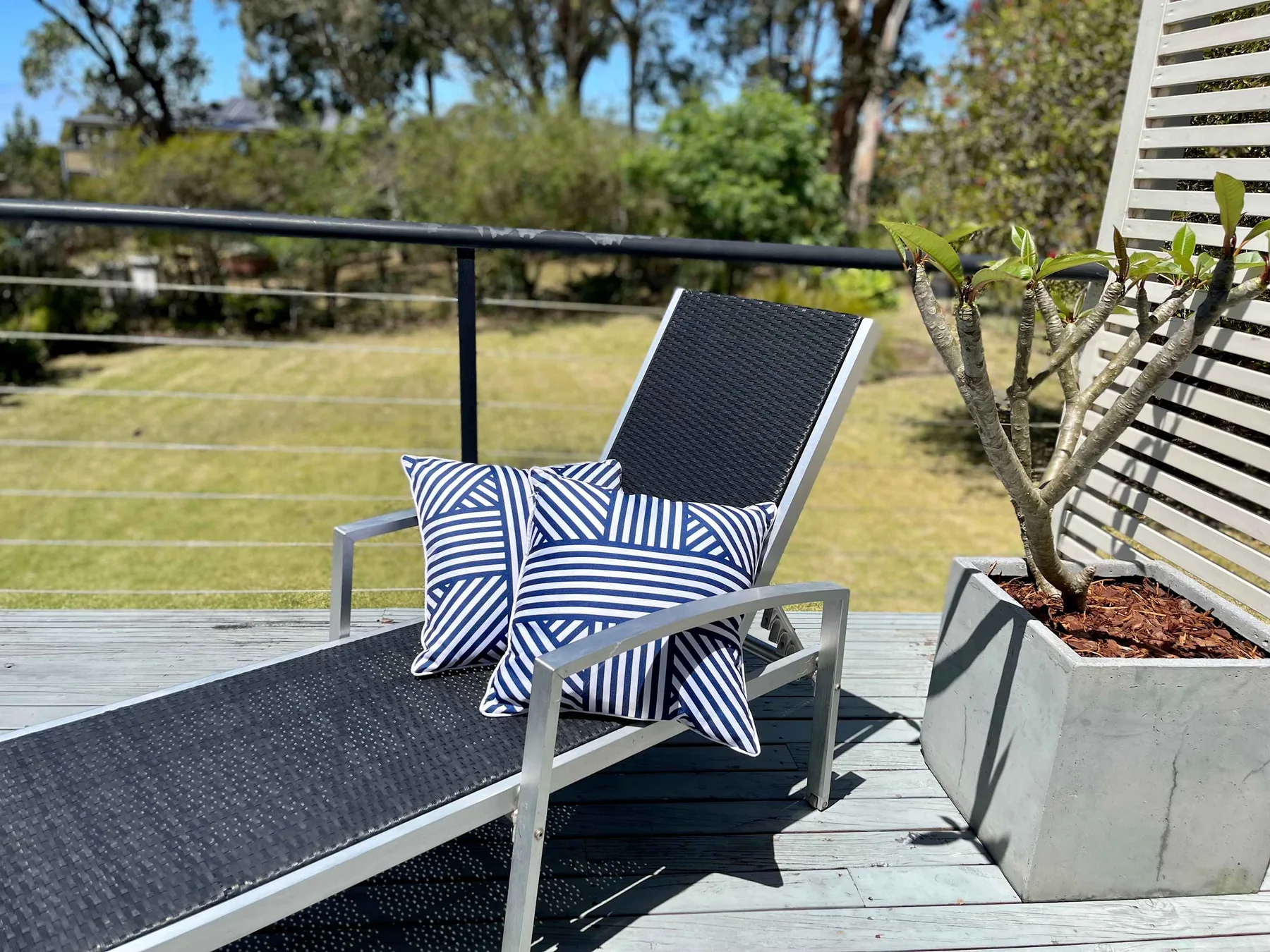 Outdoor seating on a deck with striped cushions and a potted plant.