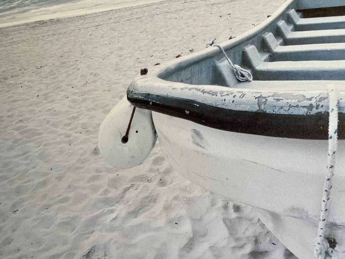 A small boat rests on a sandy beach.