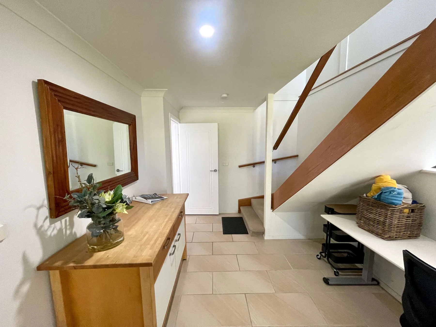 An interior hallway with a wooden staircase and a console table.