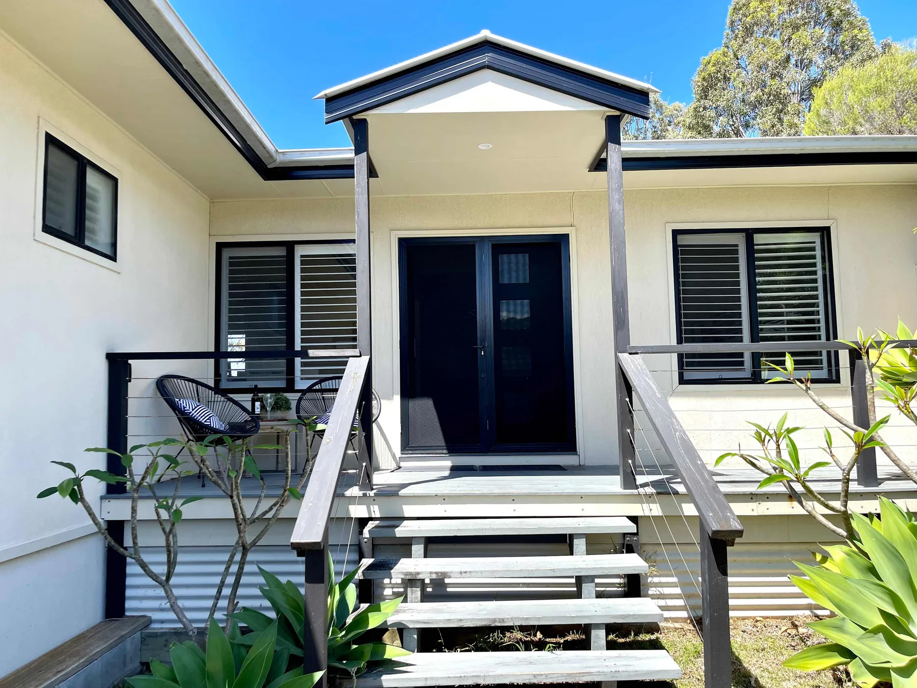 The house entrance has a covered porch, steps, and windows.