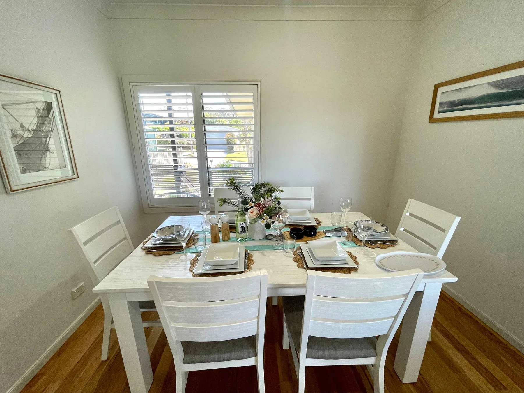 A bright dining room with a set table beside a window.
