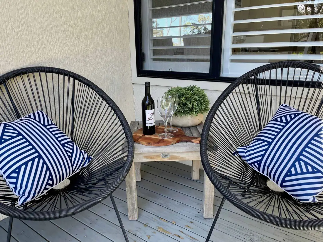 A small outdoor seating area with two chairs, striped cushions, and a side table.