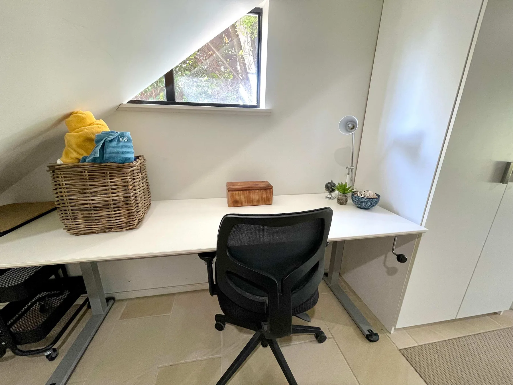 A compact workspace with a desk, office chair, and window.
