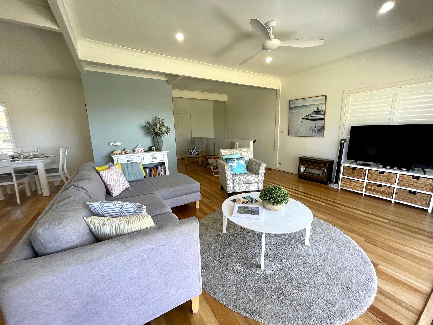 A bright living room with seating around a coffee table and a television.