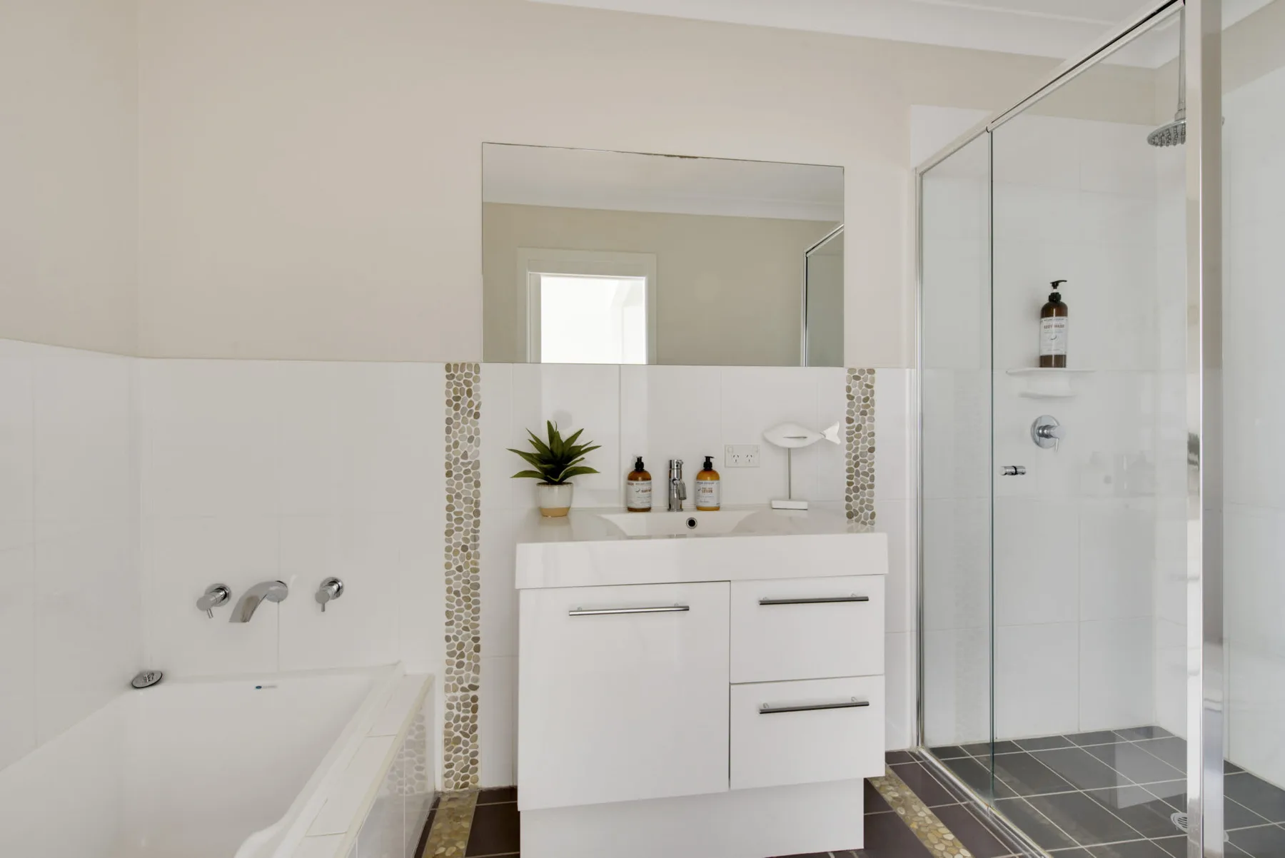 A bright bathroom with a white vanity and glass shower.