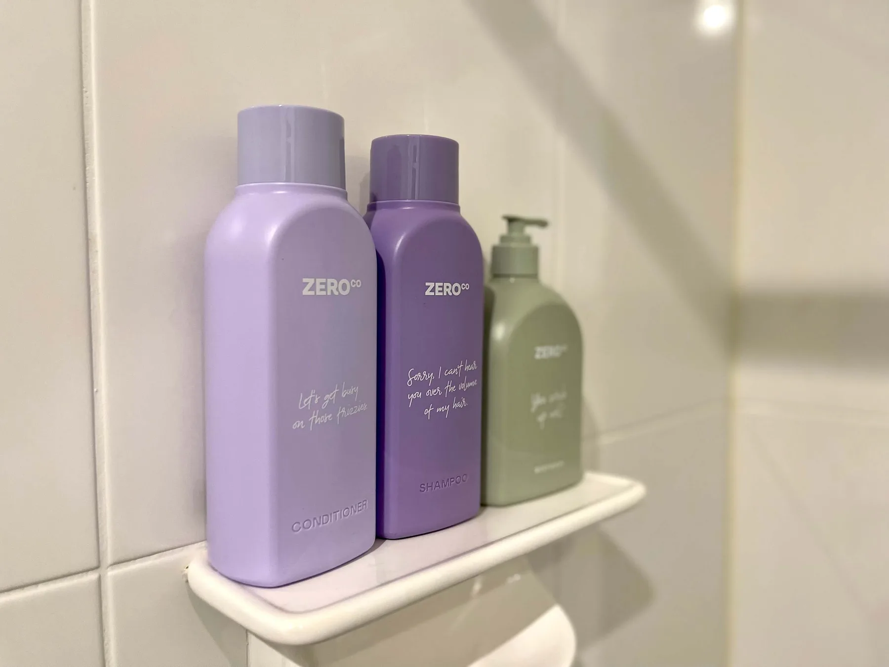 Toiletries sit on a small shelf against a tiled bathroom wall.