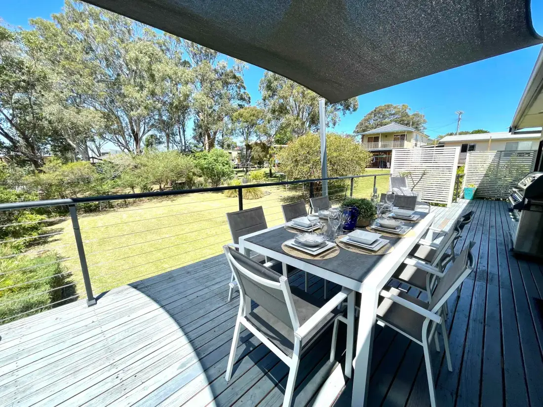 Outdoor dining area on a deck beneath a shade canopy.