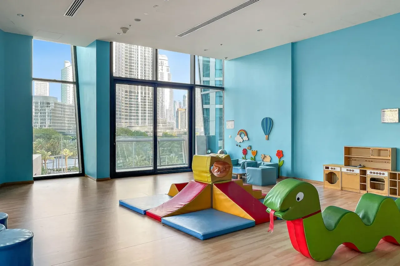 Una colorida zona de juegos interior con formas acolchadas para trepar junto a grandes ventanas.