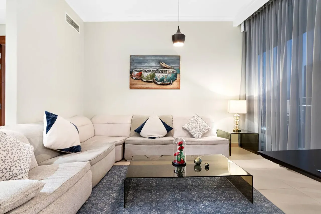 Una sala de estar con asientos seccionales, una mesa de centro y cortinas largas.