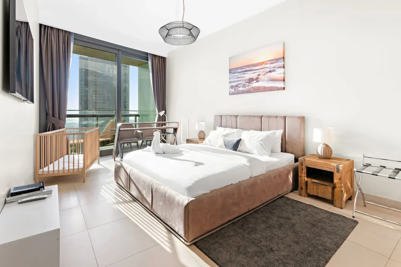 Un dormitorio luminoso con una cama grande junto a ventanales.