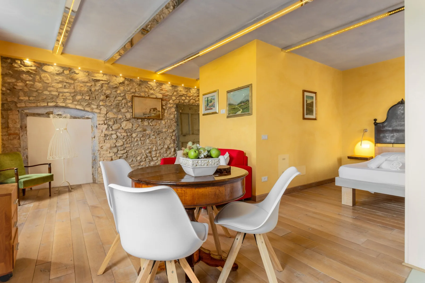 A dining area with a round table and seating beside a bedroom.