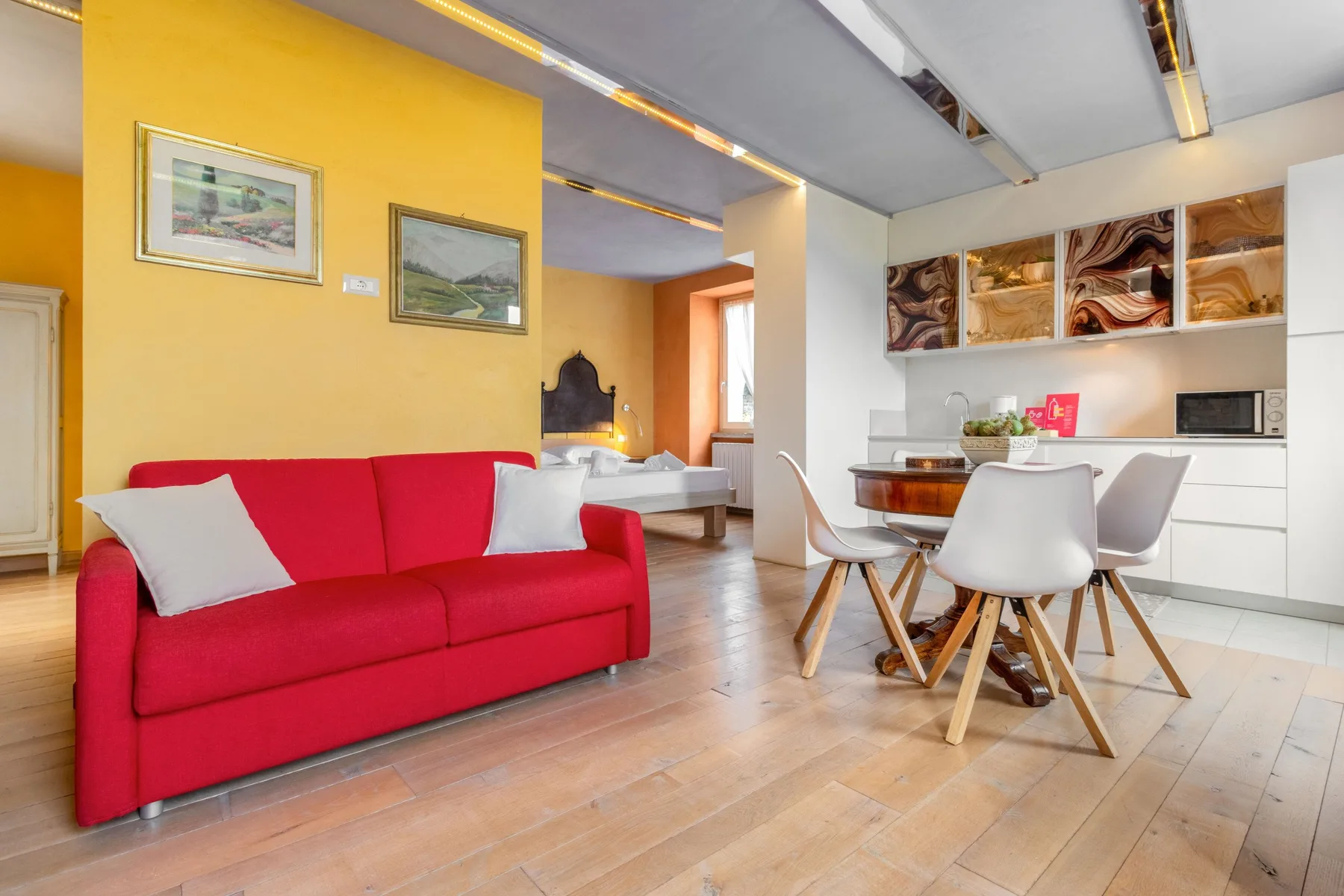 A living and dining area with a red sofa and a table with chairs.