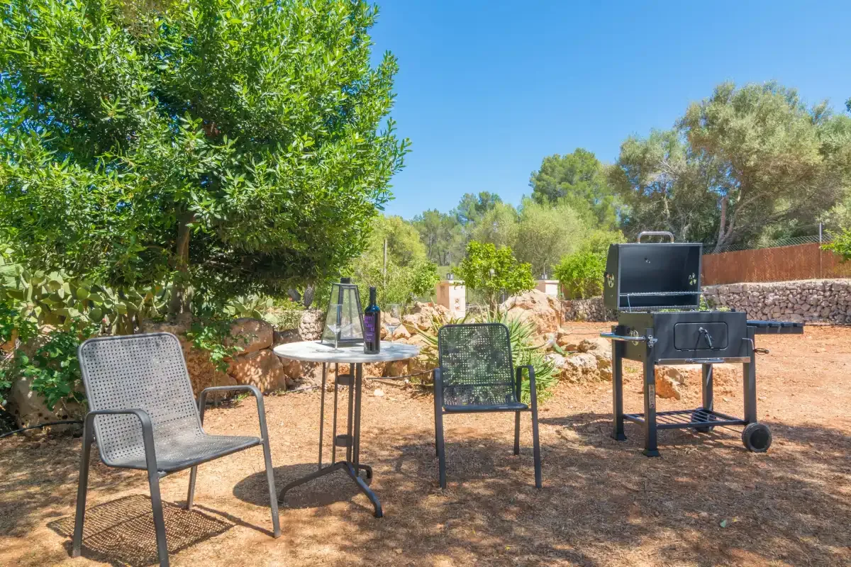 Un patio al aire libre con asientos, una mesa pequeña y una barbacoa.