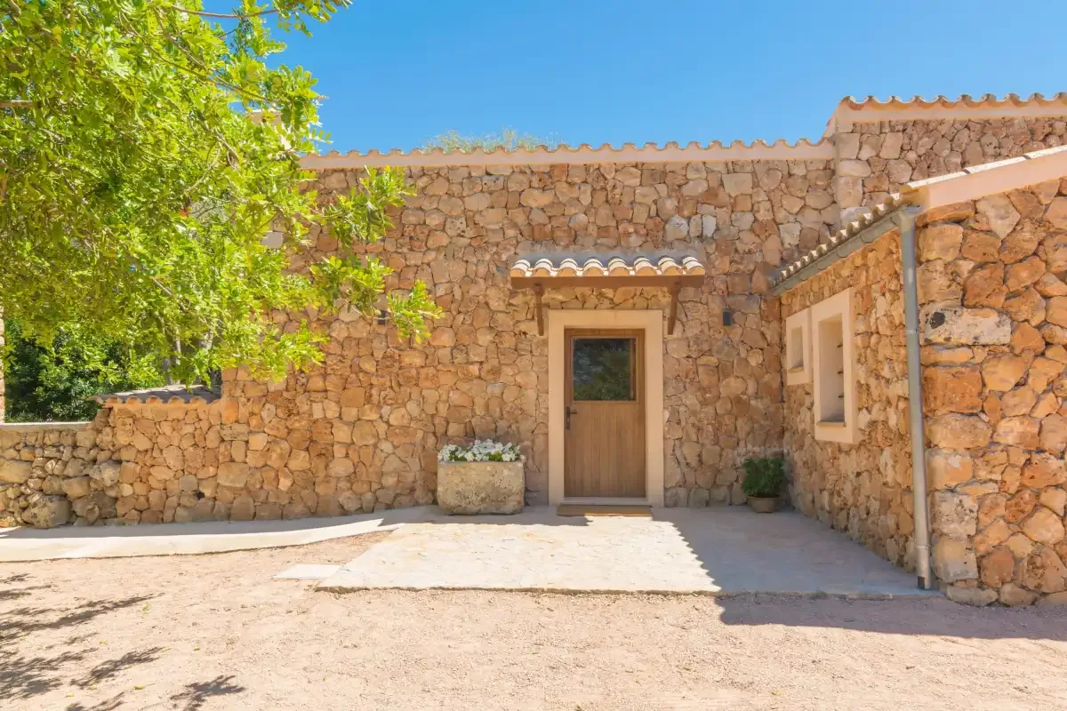 Un patio de piedra con una puerta de madera central y plantas en macetas.