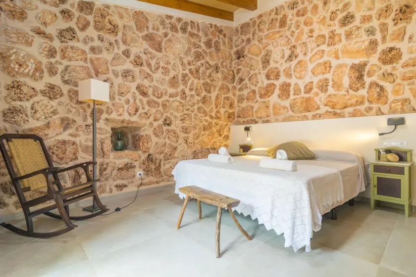 Un dormitorio con una cama y asientos junto a paredes de piedra vista.