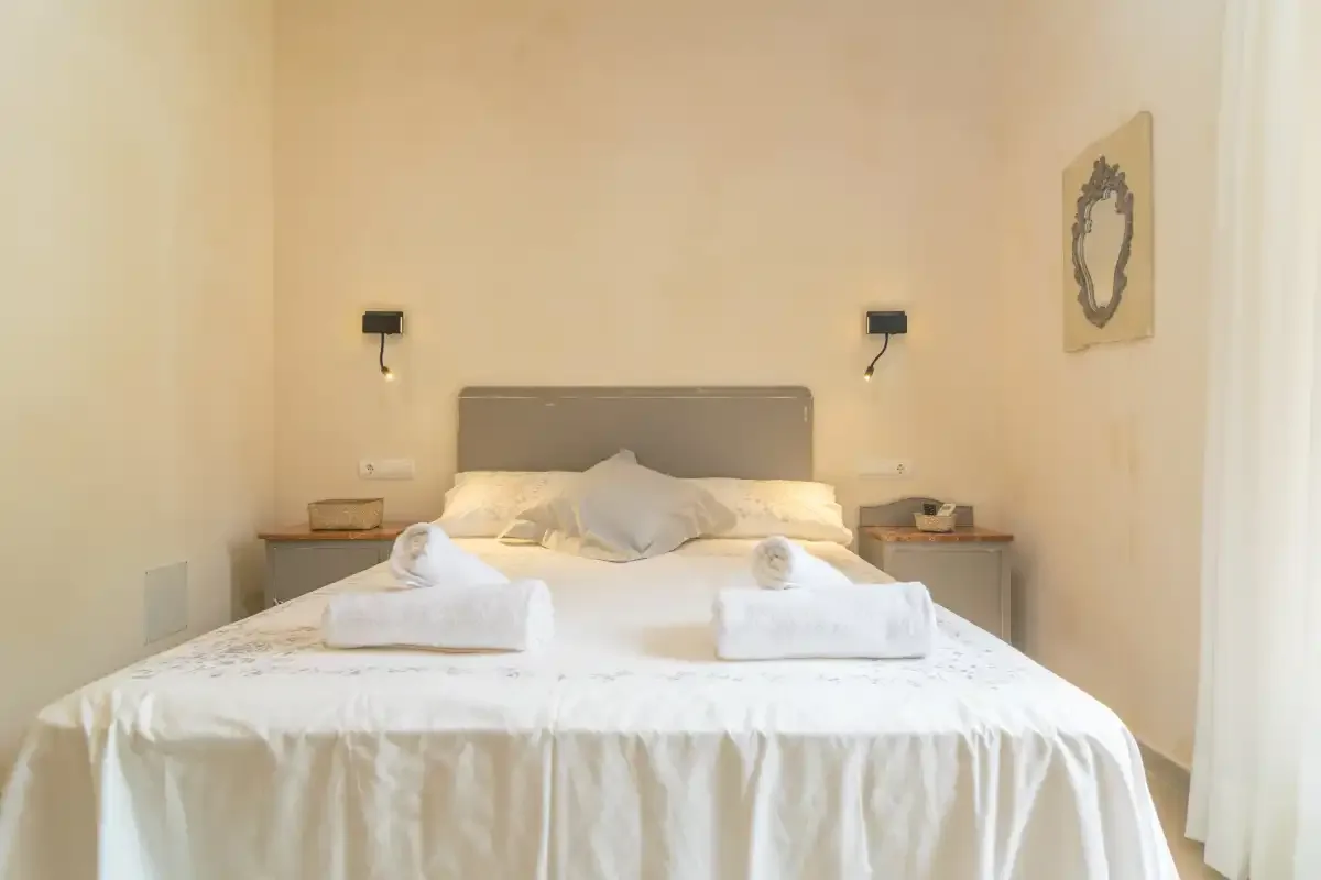 Un dormitorio con una cama bien tendida y toallas dobladas.