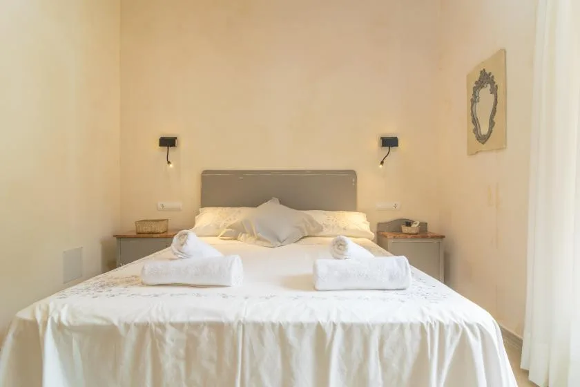 Un dormitorio con una cama ordenada y toallas dobladas.