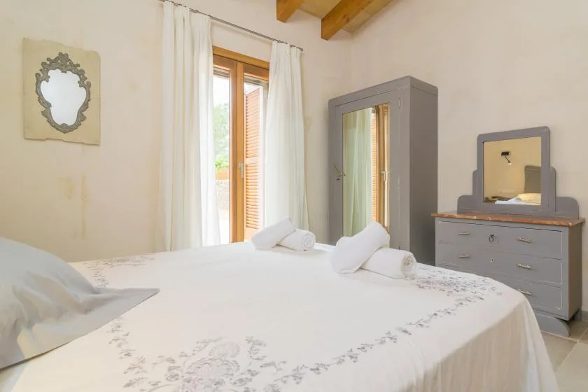 Un dormitorio con una cama bien tendida, un armario y una cómoda.