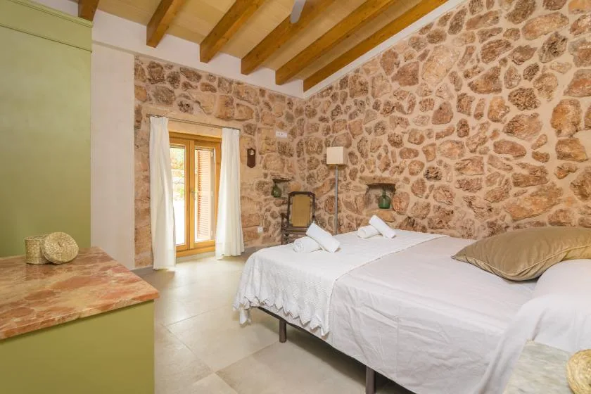 Un dormitorio con una cama, vigas de madera a la vista y paredes de piedra.