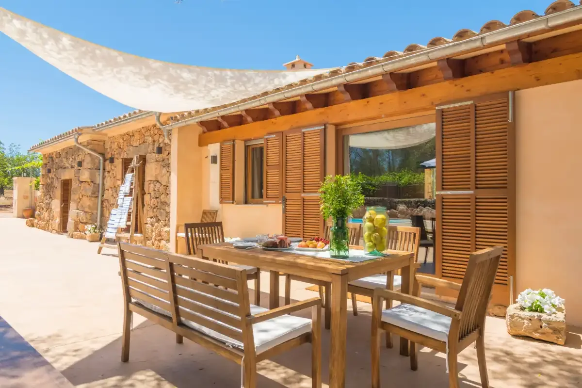 Una zona de comedor exterior con asientos de madera junto a un edificio de piedra.