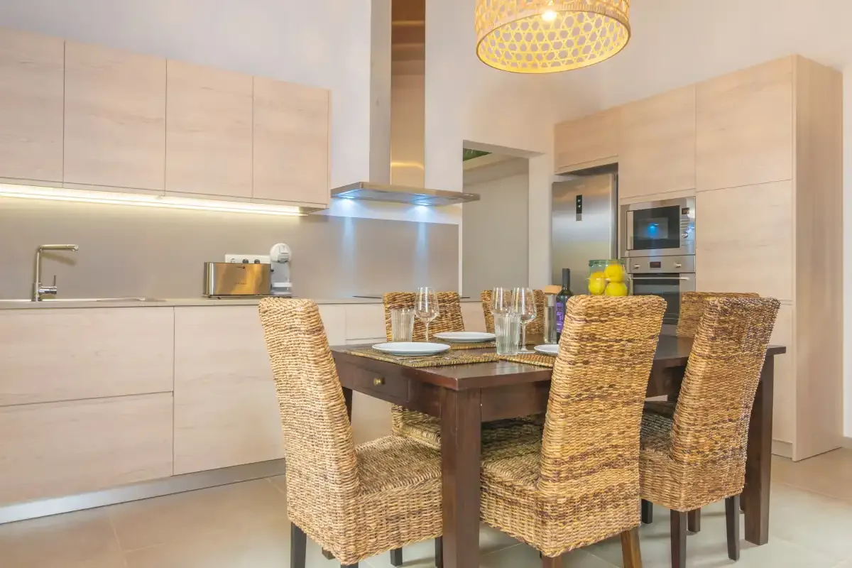 Una cocina moderna y comedor con mesa de madera y asientos de mimbre.