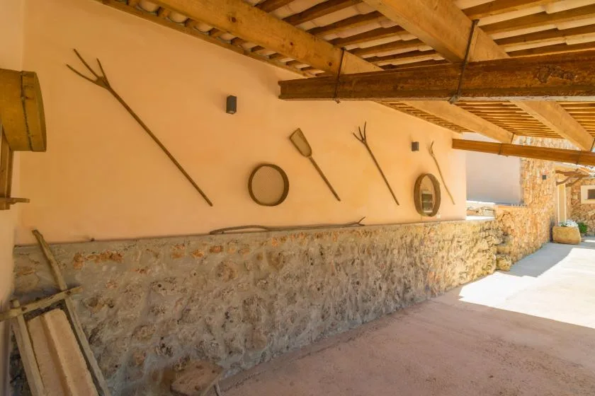 Un pasillo rústico cubierto, con paredes de piedra y vigas de madera.
