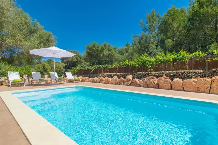 Una piscina al aire libre con asientos de descanso y una sombrilla cerca.
