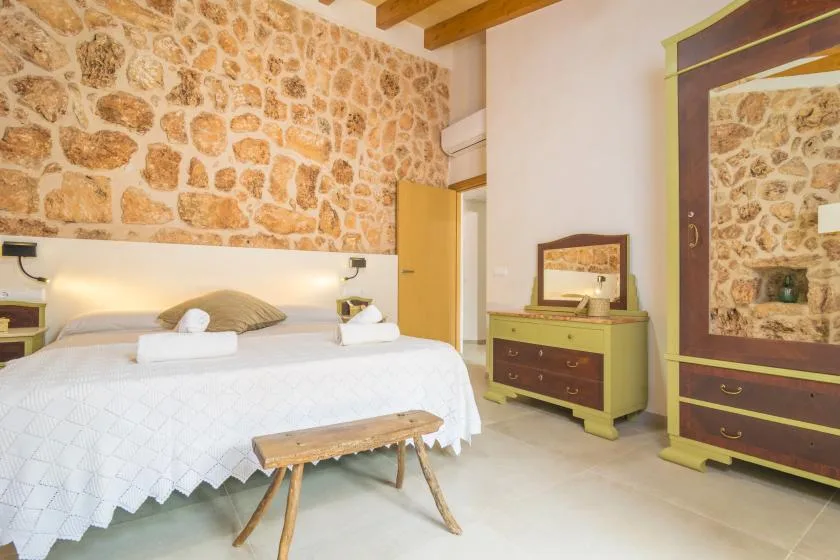 Un dormitorio con cama doble, pared de piedra y muebles de madera.