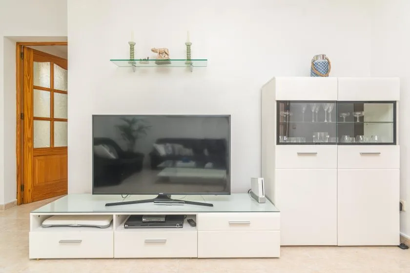 A bright living room with a television and white storage cabinets.