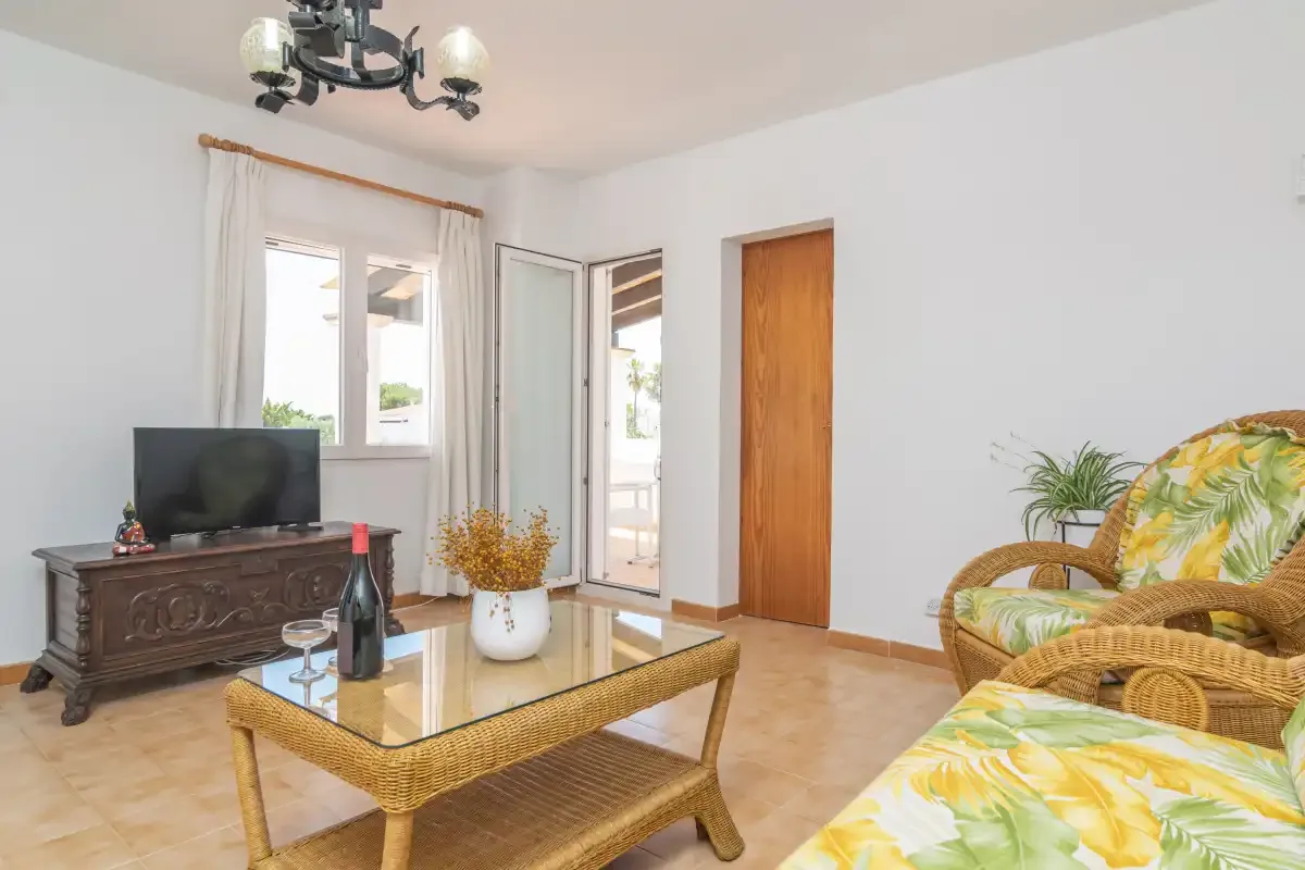 A bright living room with wicker seating and a glass-topped coffee table.