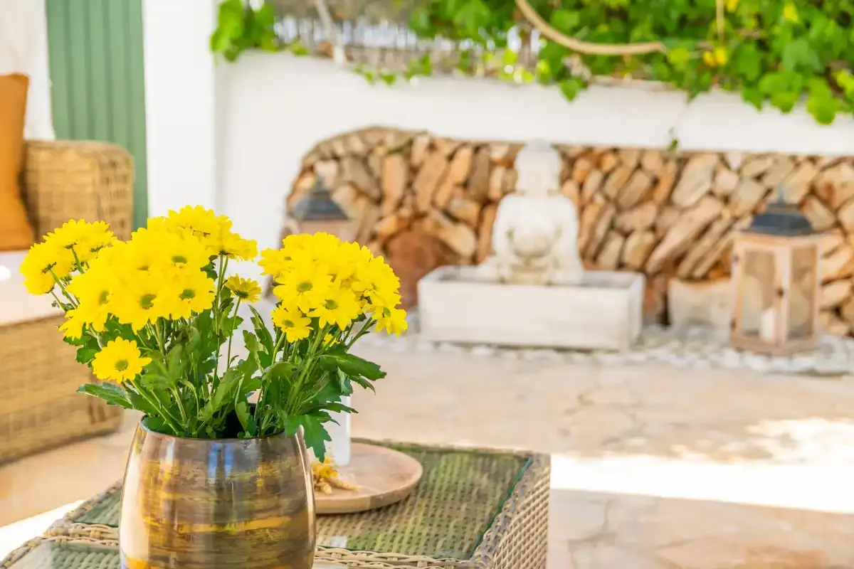 An outdoor patio seating area with yellow flowers arranged on a table.